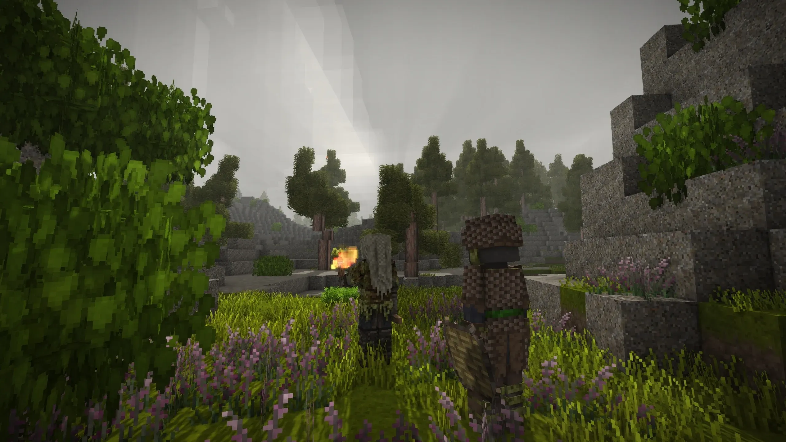 A screenshot of the game showing two player figures venturing through the world. Both are turned away from the viewer who can enjoy a cloudy sunset in the hills. One figure looks like a fierce viking warrior holding a torch, the other wears wooden armor and shield.